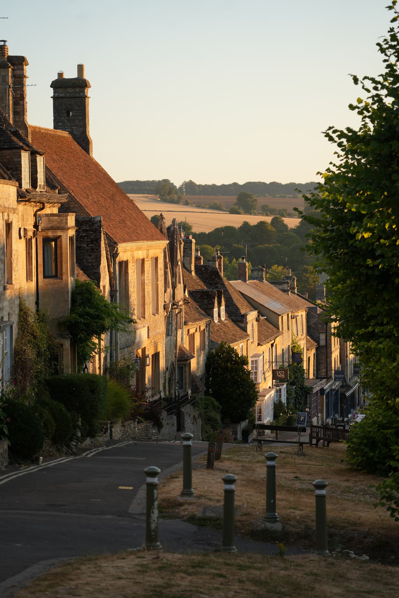 Honey-stone Cotswold village descending towards open countryside at sunset